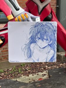 Top 10 Waifu Gifts for Your Gamer Boyfriend (That He’ll Secretly Love) | Otazoo 3 Hand-drawn sketch of Asuka Langley from Evangelion held in front of EVA unit