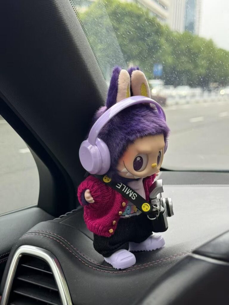 The Ultimate Labubu Collectors’ Guide (2025): Series Breakdown, Secrets, and Custom Trends 3 Custom purple-haired Labubu with headphones, cardigan, and camera sitting on car dashboard