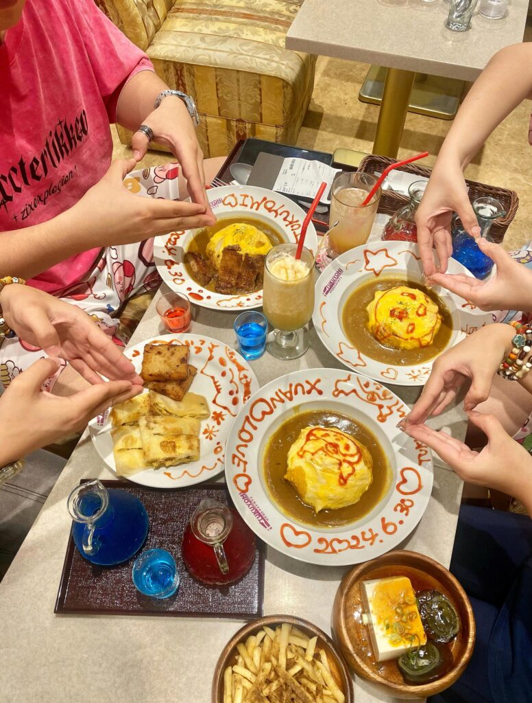 What It’s Really Like at a Maid Cafe in Japan (2025 Experience) 3 Friends performing moe moe kyun spell over omurice at a maid cafe in Tokyo