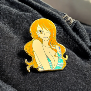 Close-up of One Piece Nami enamel pin on soft black fabric