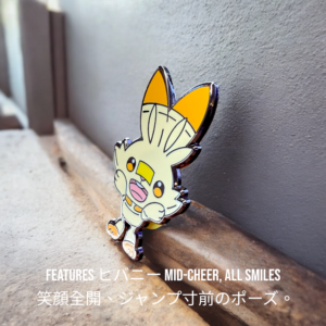 Pokemon enamel pin showing Scorbunny leaning against a stone ledge, mid-jump expression