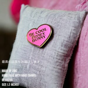Be Cool Honey Bunny enamel pin showing pink heart design on light fabric with pink tones