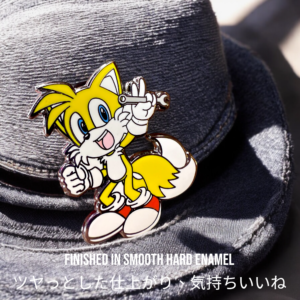 Sonic the Hedgehog enamel pin showing Tails holding wrench pinned on grey hat