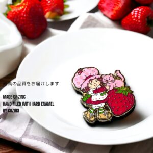 Strawberry Shortcake enamel pin showing Strawberry Shortcake with cat on white plate with strawberries in background